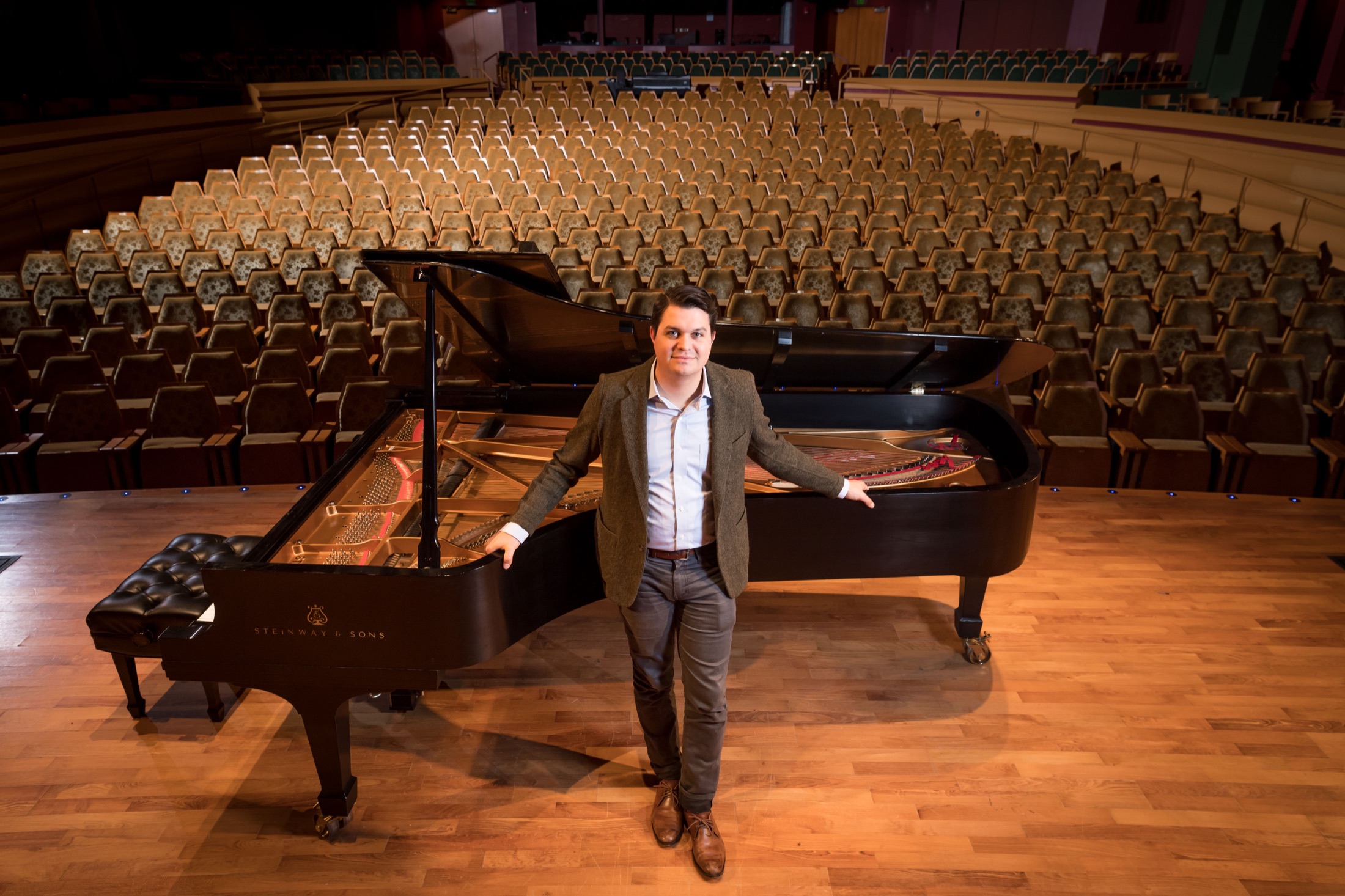 J.J. Wright standing beside a Steinway concert grand onstage